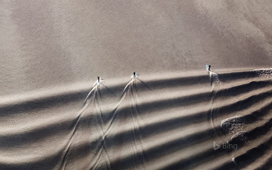 Stand-up paddleboarders riding the bore tide in Turnagain Arm, Cook Inlet, Alaska